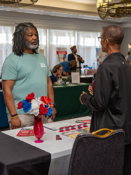 a ma asking a woman a question at the table at a veterans fair