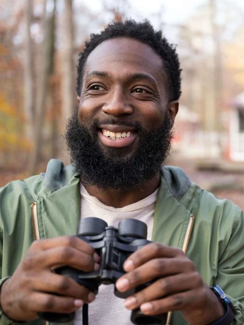 A man with binoculars birdwatching in the fall