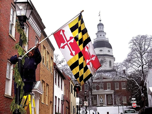 Maryland state flag being hung on a building outside the State House